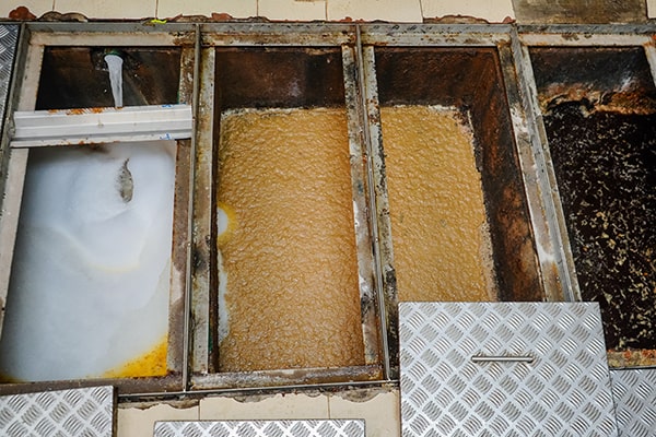 foul odors, slow drainage, and visible grease buildup are signs that your grease trap needs maintenance